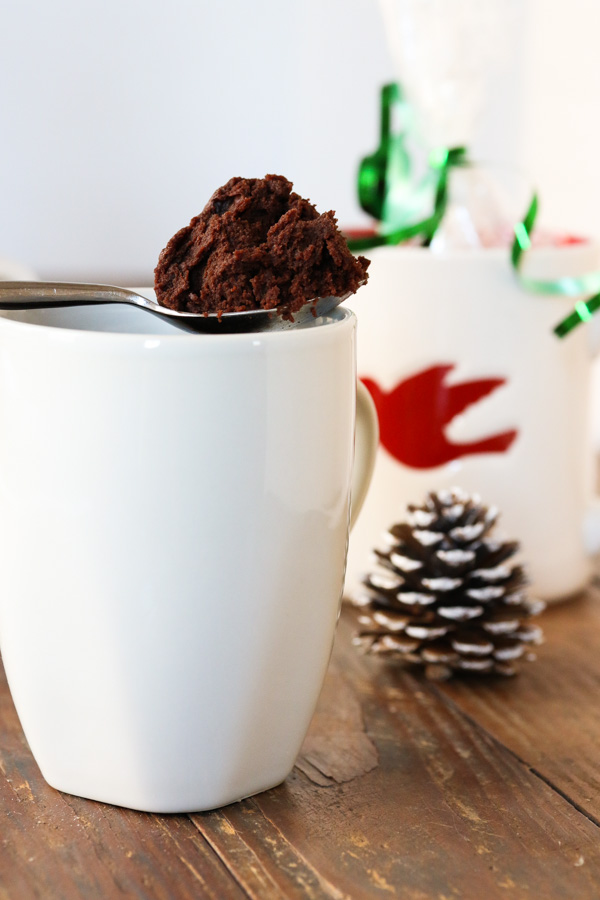 a spoonful of chocolate mug brownie, with a mug and christmas decorations in the background