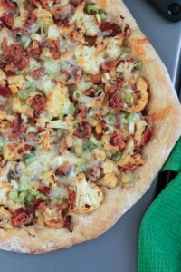 this cauliflower and bacon pizza is simple to assemble yet packed with flavor from roasted cauliflower, bacon, and cheddar cheese.