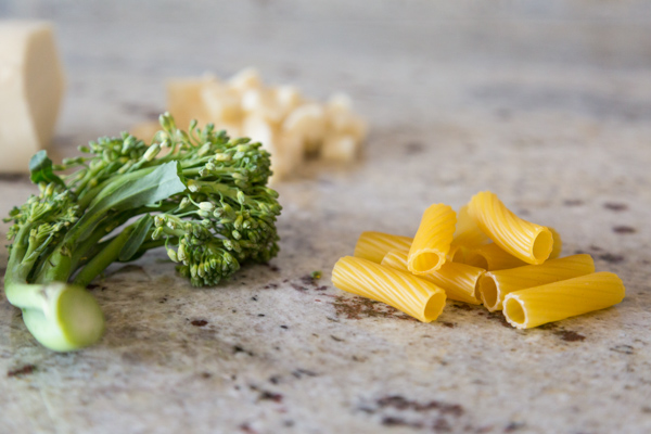 broccolini and pasta on a marble background, ready to make baked pasta with sausage and broccolini