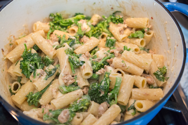 baked pasta with sausage and broccolini in a blue dutch oven