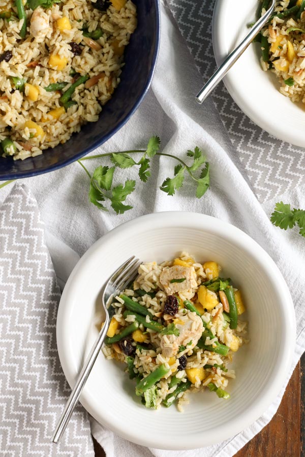 cardamom chicken and rice with mango and green beans is a perfect summer dinner all in one bowl. a zesty orange vinaigrette, raisins, and almonds add flavor and crunch. get this gluten free and dairy free recipe today!
