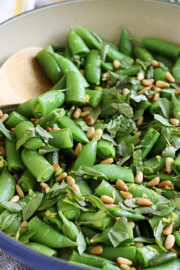 sugar snap peas with garlic scapes and basil include pine nuts and lemon zest for a delicious summer vegetable side dish. vegan/gluten free