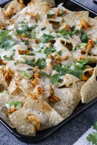 chicken tikka masala nachos are a delicious way to use up leftover chicken tikka masala! all you need is chips, cheese, scallions, cilantro, and tikka masala. gluten free, easy, and fast. grab this recipe and give your leftovers some new life!