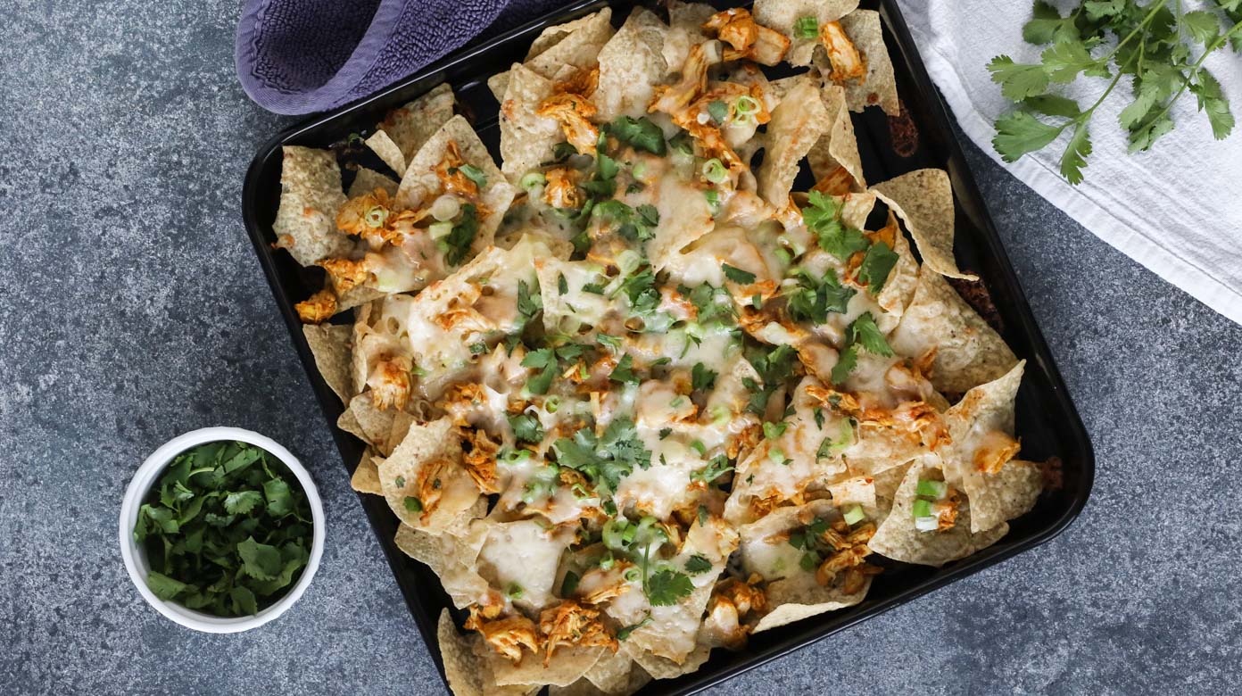 chicken tikka masala nachos are a delicious way to use up leftover chicken tikka masala! all you need is chips, cheese, scallions, cilantro, and tikka masala. gluten free, easy, and fast. grab this recipe and give your leftovers some new life!