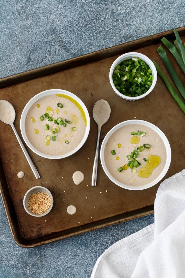two bowls of creamy miso roasted mushroom soup with scallions, sesame seeds, and olive oil