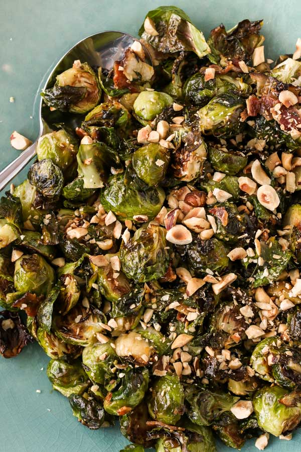 close-up of roasted brussels sprouts with bacon and figs on a teal plate