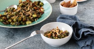 roasted brussels sprouts with bacon and figs in a white bowl, with more brussels sprouts in the background