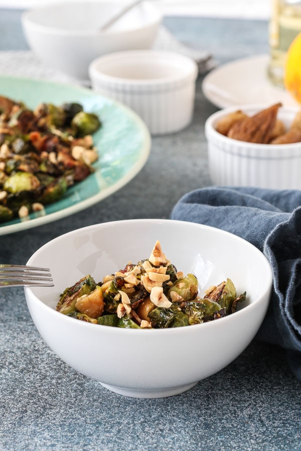 roasted brussels sprouts with bacon and figs in a white bowl
