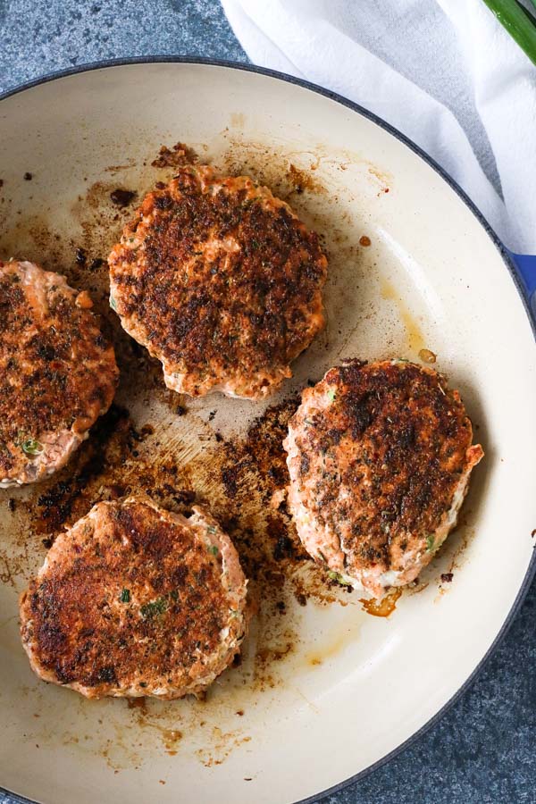 overhead view of cajun salmon burgers cooked in an enameled skillet
