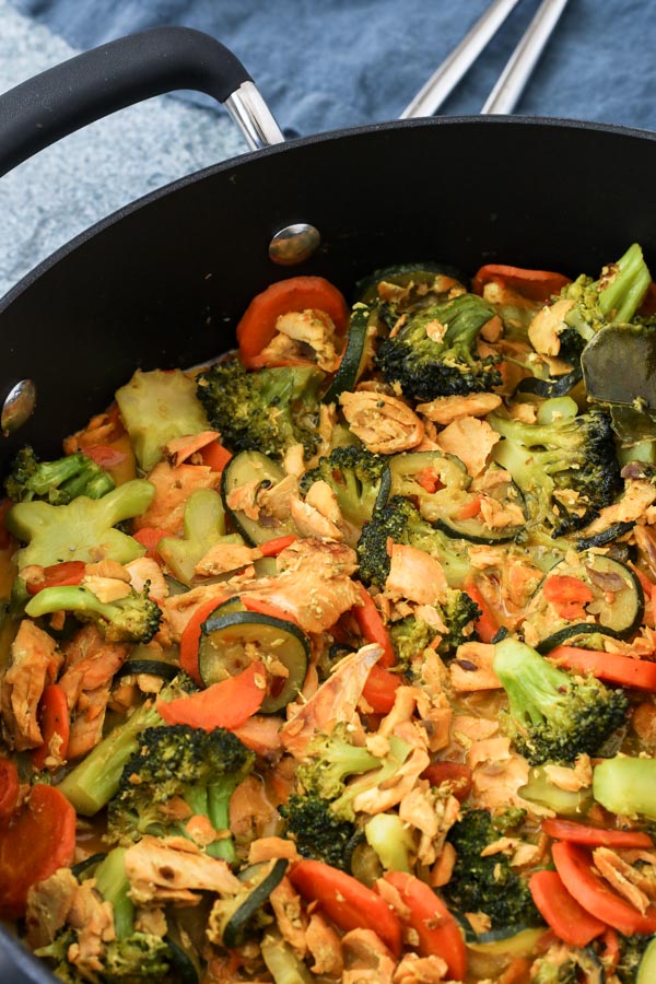 indi-thai fish curry with salmon, vegetables, and coconut milk in a white bowl