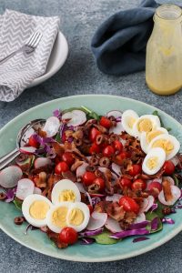 spinach salad with bacon and hard boiled eggs on an aqua serving plate
