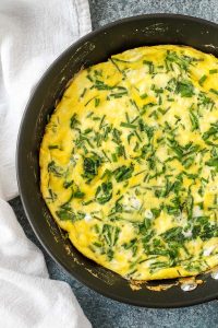arugula, goat cheese, and chive frittata in a nonstick skillet