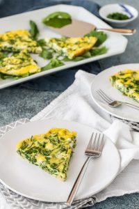 arugula, goat cheese, and chive frittata on a white plate and serving platter
