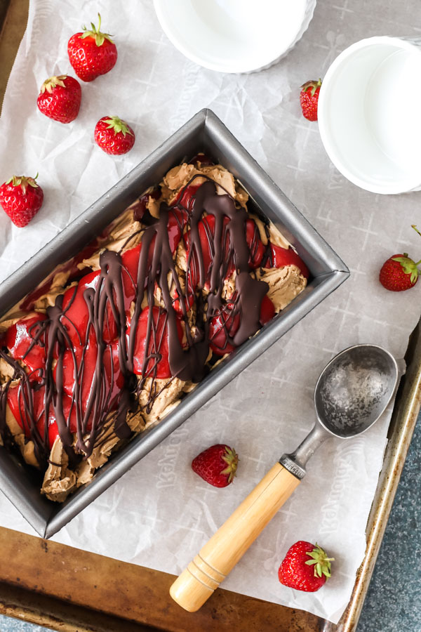 homemade hazelnut ice cream with strawberry and chocolate swirls in a metal loaf pan.