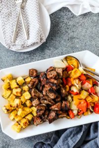 grilled chopped pork, pineapple, and peppers on a white platter