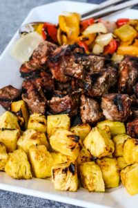 grilled chopped pork, pineapple, and peppers on a white platter