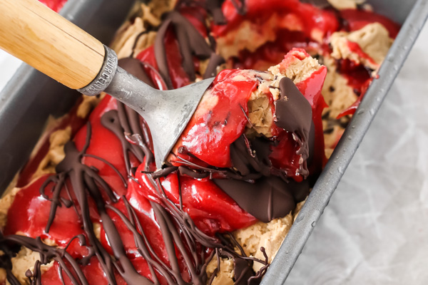 hazelnut ice cream with strawberry and chocolate swirls being scooped