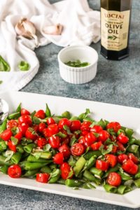sugar snap peas with marinated cherry tomatoes on a white platter