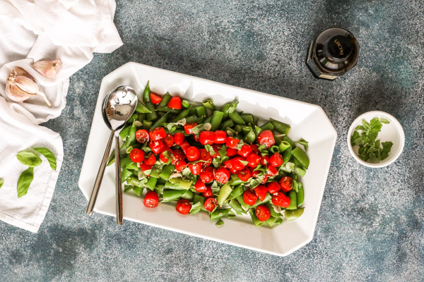 sugar snap peas with marinated cherry tomatoes on a white platter